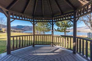 Deck with a gazebo, a yard, and a water and mountain view