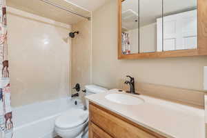 Full bathroom featuring shower / tub combo, vanity, a textured ceiling, and toilet