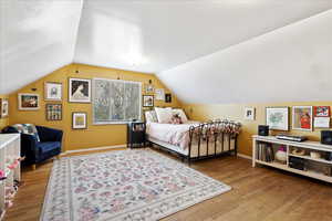 Bedroom featuring hardwood flooring and vaulted ceiling