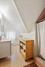 Bathroom featuring vanity, lofted ceiling, toilet, and a shower with curtain