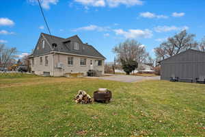 Rear view of house with a yard, central air condition unit, and an outdoor fire pit