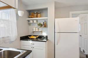 Kitchen with pendant lighting, white cabinets, and white fridge