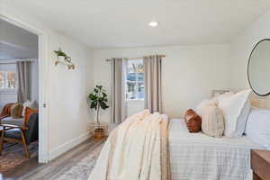 Bedroom with a textured ceiling, hardwood / wood-style flooring, and multiple windows