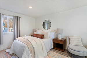 Bedroom with a textured ceiling and light hardwood / wood-style floors