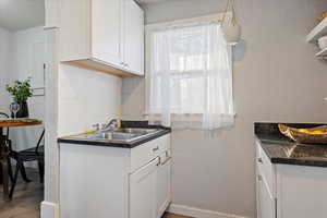 Kitchen featuring decorative backsplash, wood-type flooring, white cabinets, and sink