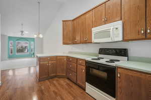 Kitchen with lofted ceiling, light hardwood / wood-style flooring, electric range oven, hanging light fixtures, and kitchen peninsula