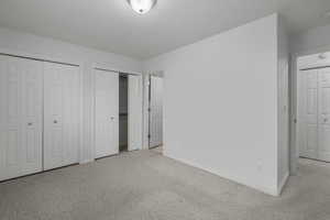 Unfurnished bedroom with light colored carpet and multiple closets