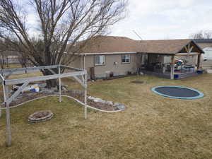 Rear view of house featuring a trampoline and a lawn