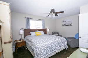 Carpeted bedroom featuring ceiling fan and sitting area