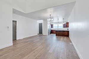 Unfurnished living room featuring a chandelier and light wood-type flooring