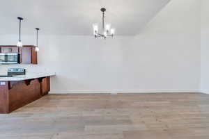 Kitchen featuring light wood-type flooring, stainless steel appliances, and hanging light fixtures