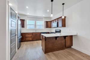 Kitchen featuring sink, a breakfast bar area, light hardwood / wood-style flooring, kitchen peninsula, and stainless steel appliances