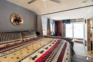 Bedroom with ceiling fan, wood-type flooring, a textured ceiling, and vaulted ceiling