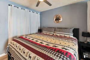 Bedroom featuring ceiling fan, wood-type flooring, and a textured ceiling