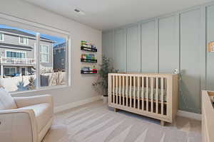 Carpeted bedroom with a crib and a textured ceiling