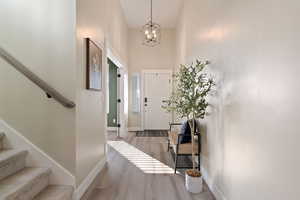 Foyer entrance with a towering ceiling, a notable chandelier, and light hardwood / wood-style flooring