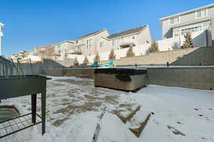 Yard layered in snow with a hot tub