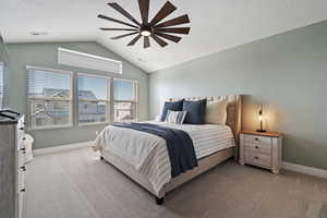 Carpeted bedroom featuring ceiling fan, vaulted ceiling, and a textured ceiling