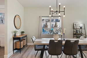 Dining room with a healthy amount of sunlight, light hardwood / wood-style flooring, and a notable chandelier