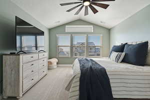 Bedroom featuring light carpet, ceiling fan, vaulted ceiling, and a textured ceiling