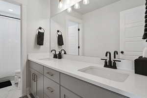 Bathroom with vanity, curtained shower, and toilet