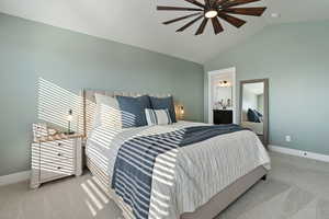 Carpeted bedroom featuring vaulted ceiling, ceiling fan, and ensuite bathroom