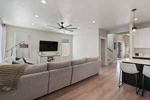 Living room featuring ceiling fan, light hardwood / wood-style flooring, and a textured ceiling