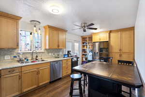 Updated Kitchen featuring sink, backsplash, hanging light fixtures, stainless steel appliances, and dark wood-type flooring