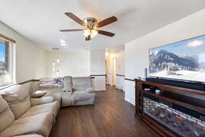 Living room featuring ceiling fan, dark wood-type flooring, and fresh paint.