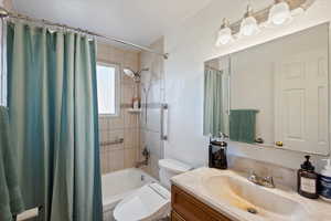 Full bathroom featuring shower / bath combination with curtain, vanity, and toilet