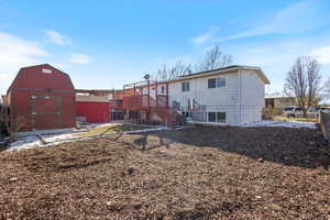 Back of house with a wooden deck and a storage units