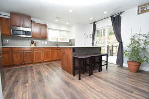 Kitchen featuring plenty of natural light, a breakfast bar, dark wood-type flooring, and decorative backsplash