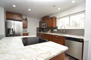 Kitchen featuring dark hardwood / wood-style floors, tasteful backsplash, sink, a center island, and stainless steel appliances