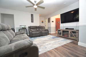 Living room with dark hardwood / wood-style flooring and ceiling fan