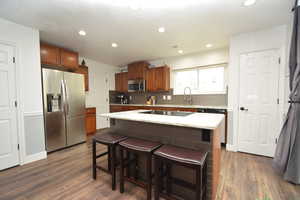 Kitchen with a kitchen breakfast bar, a center island, dark hardwood / wood-style flooring, and black appliances