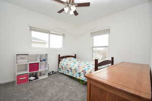 Bedroom featuring multiple windows, dark colored carpet, lofted ceiling, and ceiling fan