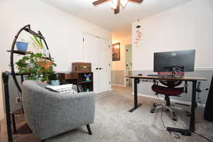 Carpeted home office featuring ceiling fan