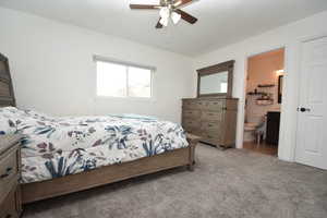 Bedroom featuring light carpet, ceiling fan, and ensuite bathroom