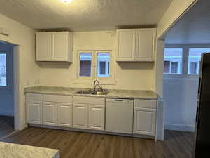 Kitchen with dark wood-style floors, a sink, white cabinetry, freestanding refrigerator, and dishwasher