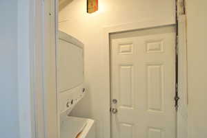 Laundry room featuring stacked washer and clothes dryer.  The main floor unit has access from bedroom 2 and the upstairs though they have their own washer and dryer hookup can access from the exterior.