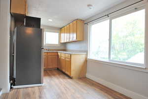 Kitchen featuring light brown cabinetry, sink, light hardwood / wood-style flooring, and stainless steel refrigerator