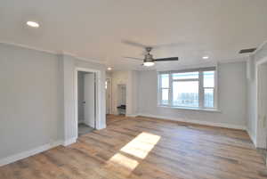 Living room with crown molding, ceiling fan, and light hardwood / wood-style floors