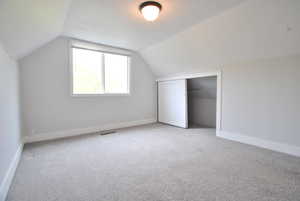 Additional living space featuring vaulted ceiling and light carpet