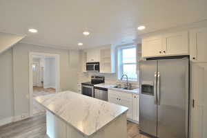 Kitchen with white cabinetry, appliances with stainless steel finishes, a center island, and sink