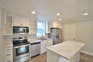 Kitchen featuring white cabinetry, stainless steel appliances, sink, and decorative backsplash