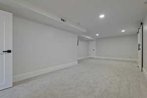 Carpeted empty room featuring a barn door