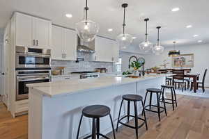 Kitchen with white cabinetry, pendant lighting, range, and a spacious island