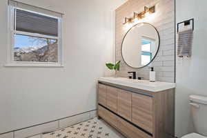 Bathroom with tile patterned flooring, vanity, backsplash, and toilet