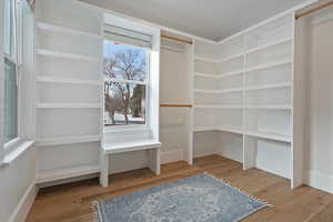 Walk in closet with hardwood / wood-style floors