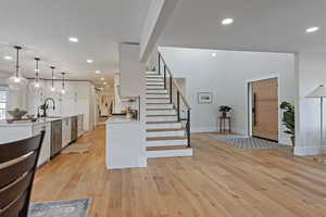 Kitchen with sink, white cabinetry, dishwasher, pendant lighting, and light hardwood / wood-style floors